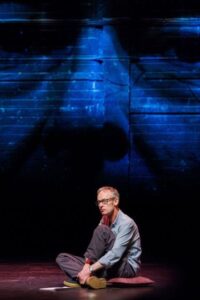 Actor sitting on a dark stage